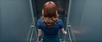 Movie still from “Severance” (2022), created by Dan Erickson – A woman with long red hair is ascending an escalator; Medium shot, Overhead angle