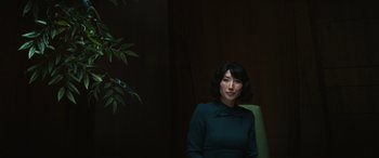 Movie still from “Severance” (2022), created by Dan Erickson – A woman sitting in a chair in front of a tree; Medium shot, Low angle