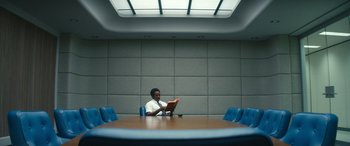 Movie still from “Severance” (2022), created by Dan Erickson – A man sitting at a table in front of a laptop computer; Wide shot, High angle