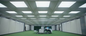 Movie still from “Severance” (2022), created by Dan Erickson – A man sitting at a computer desk in an office setting; Extreme Wide shot, Low angle