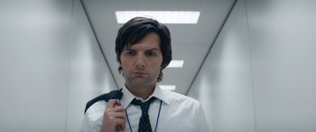 Movie still from “Severance” (2022), created by Dan Erickson – A man in a white dress shirt and tie holding a black tie; Close Up shot, Low angle