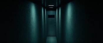 Movie still from “Severance” (2022), created by Dan Erickson – A door to a dark room with lights on the ceiling; Wide shot, High angle