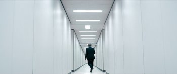 Movie still from “Severance” (2022), created by Dan Erickson – A man in a suit walking down a long hallway; Wide shot, Low angle