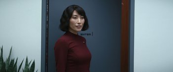 Movie still from “Severance” (2022), created by Dan Erickson – A woman in a red shirt standing in front of a blue wall; Close Up shot, Over the shoulder angle