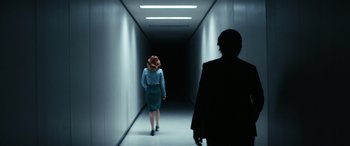 Movie still from “Severance” (2022), created by Dan Erickson – A woman in a blue dress walking down a hallway; Wide shot, Over the shoulder angle