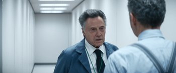 Movie still from “Severance” (2022), created by Dan Erickson – An older man wearing a suit and tie in an office building; Close Up shot, Over the shoulder angle