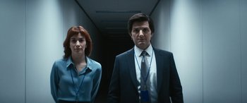 Movie still from “Severance” (2022), created by Dan Erickson – A man and a woman standing next to each other in a hallway; Medium shot, Low angle