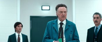 Movie still from “Severance” (2022), created by Dan Erickson – An older man wearing a blue jacket and a black tie; Medium shot, Over the shoulder angle