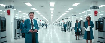 Movie still from “Severance” (2022), created by Dan Erickson – A man in a suit and tie standing in a room; Wide shot, Low angle