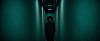 Movie still from “Severance” (2022), created by Dan Erickson – A woman standing in a dark hallway holding a pair of walking sticks; Wide shot, Low angle