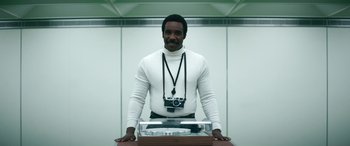 Movie still from “Severance” (2022), created by Dan Erickson – A man in a white shirt is holding a record player; Medium shot, Low angle