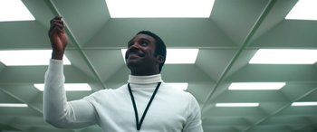 Movie still from “Severance” (2022), created by Dan Erickson – A man wearing a white shirt and a black neck cord; Medium shot, Low angle