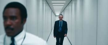 Movie still from “Severance” (2022), created by Dan Erickson – A man in a suit and tie walking down a long hallway; Medium shot, Over the shoulder angle