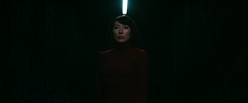 Movie still from “Severance” (2022), created by Dan Erickson – A woman standing in the dark with a light shining above her head; Medium shot, Low angle