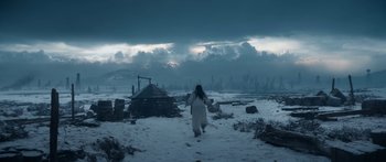 Movie still from “1899” (2022), created by Jantje Friese – A woman walking through the snow in front of a hut; Extreme Wide shot, Low angle