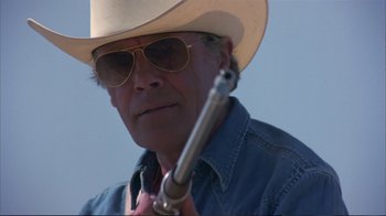 Movie still from “Sexy Beast” (2000), directed by Jonathan Glazer – A man wearing a cowboy hat and holding a gun; Close Up shot, Low angle