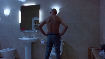 Movie still from “Sexy Beast” (2000), directed by Jonathan Glazer – A man standing in front of a bathroom mirror; Medium shot, Low angle