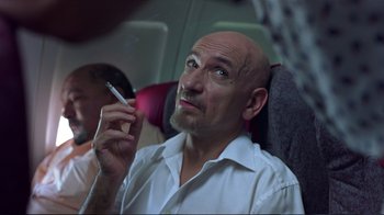 Movie still from “Sexy Beast” (2000), directed by Jonathan Glazer – A man smoking a cigarette while sitting on a plane; Close Up shot, Low angle