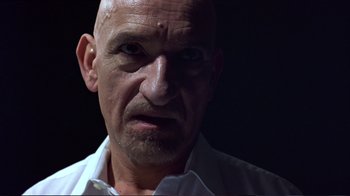Movie still from “Sexy Beast” (2000), directed by Jonathan Glazer – An older man with a shaved head and a white shirt; Close Up shot, Low angle