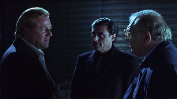 Movie still from “Sexy Beast” (2000), directed by Jonathan Glazer – A group of men standing next to each other in the dark; Medium shot, Over the shoulder angle
