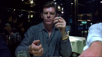 Movie still from “Sexy Beast” (2000), directed by Jonathan Glazer – A man sitting at a table holding a cell phone to his ear; Close Up shot, Low angle