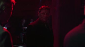 Movie still from “Sexy Beast” (2000), directed by Jonathan Glazer – A man in a suit standing in a dark room; Medium shot, Over the shoulder angle