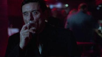 Movie still from “Sexy Beast” (2000), directed by Jonathan Glazer – A person wearing a suit and smoking a cigarette; Close Up shot, Low angle