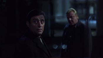 Movie still from “Sexy Beast” (2000), directed by Jonathan Glazer – A man in a suit and tie next to another man in a black jacket; Close Up shot, Over the shoulder angle