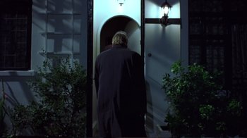 Movie still from “Sexy Beast” (2000), directed by Jonathan Glazer – A man in a black jacket is standing in front of a door; Medium shot, Low angle