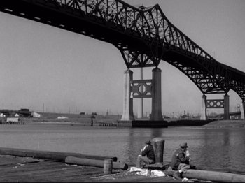 Movie still from “Shadow of a Doubt” (1943), directed by Alfred Hitchcock – Two men sitting on a dock under a bridge; Extreme Wide shot, Low angle