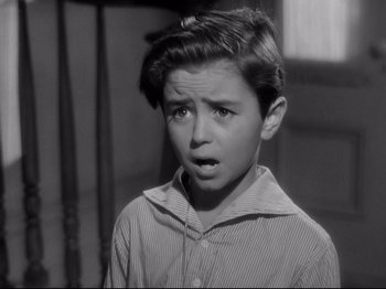 Movie still from “Shadow of a Doubt” (1943), directed by Alfred Hitchcock – A young boy in a striped shirt is looking at the camera; Close Up shot, High angle