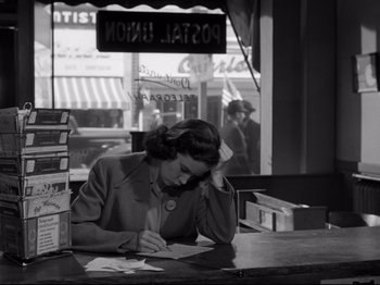 Movie still from “Shadow of a Doubt” (1943), directed by Alfred Hitchcock – A woman sitting at a table writing on a piece of paper; Medium shot, High angle