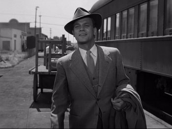 Movie still from “Shadow of a Doubt” (1943), directed by Alfred Hitchcock – A black and white photo of a man in a suit and hat; Medium shot, Low angle