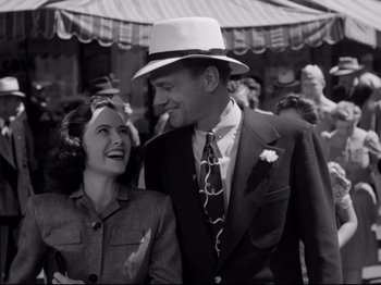 Movie still from “Shadow of a Doubt” (1943), directed by Alfred Hitchcock – A man and a woman are smiling for the camera; Medium shot, Low angle