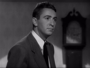 Movie still from “Shadow of a Doubt” (1943), directed by Alfred Hitchcock – Black and white photograph of a man wearing a suit and tie; Close Up shot, Low angle