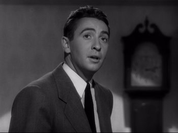 Movie still from “Shadow of a Doubt” (1943), directed by Alfred Hitchcock – A black and white photo of a man wearing a suit and tie; Close Up shot, Low angle