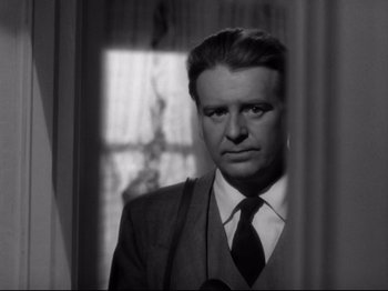 Movie still from “Shadow of a Doubt” (1943), directed by Alfred Hitchcock – A black and white photo of a man in a suit and tie; Close Up shot, Low angle