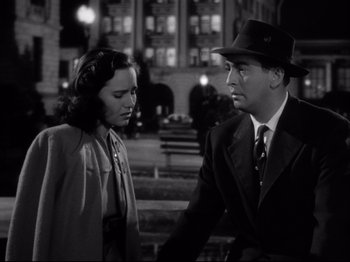 Movie still from “Shadow of a Doubt” (1943), directed by Alfred Hitchcock – A man and a woman standing next to each other on a street; Medium shot, Low angle
