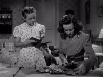 Movie still from “Shadow of a Doubt” (1943), directed by Alfred Hitchcock – Two young women looking at papers on a table; Medium shot, High angle