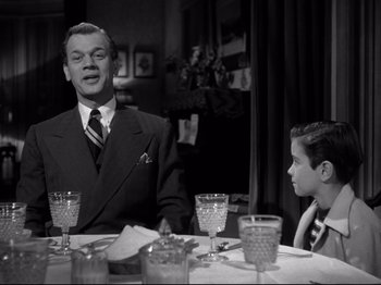 Movie still from “Shadow of a Doubt” (1943), directed by Alfred Hitchcock – A man and a boy sitting at a dinner table; Medium shot, Low angle