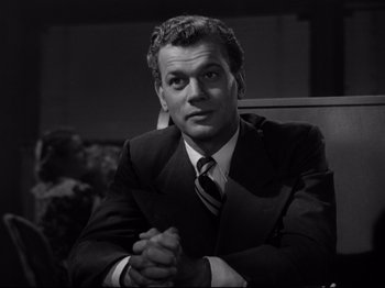 Movie still from “Shadow of a Doubt” (1943), directed by Alfred Hitchcock – Black and white photograph of a man in a suit and tie; Close Up shot, Low angle