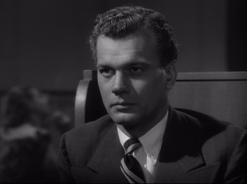 Movie still from “Shadow of a Doubt” (1943), directed by Alfred Hitchcock – Black and white photograph of a man wearing a suit and tie; Close Up shot, Low angle