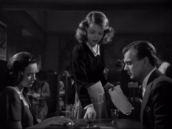 Movie still from “Shadow of a Doubt” (1943), directed by Alfred Hitchcock – A black - and - white photo of a woman and two men; Medium shot, Low angle