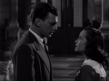 Movie still from “Shadow of a Doubt” (1943), directed by Alfred Hitchcock – A man and a woman standing next to each other on a street; Medium shot, Low angle