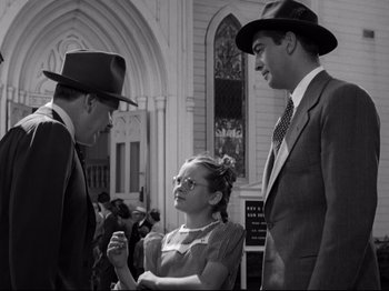 Movie still from “Shadow of a Doubt” (1943), directed by Alfred Hitchcock – Two men and a woman talking to each other in front of a building; Medium shot, Low angle