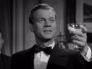 Movie still from “Shadow of a Doubt” (1943), directed by Alfred Hitchcock – A man in a suit and bow tie holding a glass; Close Up shot, Low angle