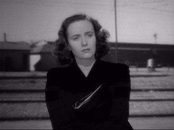 Movie still from “Shadow of a Doubt” (1943), directed by Alfred Hitchcock – A woman in a black jacket holding a purse; Close Up shot, Low angle