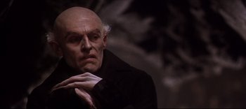 An old man with a bald head is looking to his left