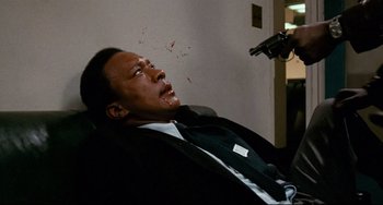 Movie still from “Shaft” (1971), directed by Gordon Parks – A man in a suit and tie with a gun in his hand; Medium shot, Low angle