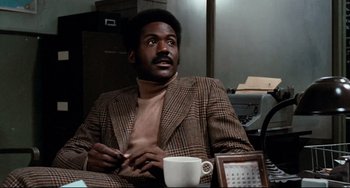 Movie still from “Shaft” (1971), directed by Gordon Parks – A man sitting in front of a coffee cup; Close Up shot, Low angle